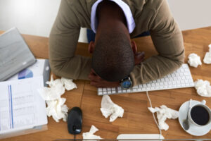 AC and Allergies - High angle shot of a young businessman feeling ill at his work desk