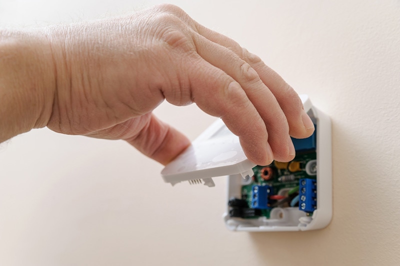 Tips to Troubleshoot Your Thermostat, hand opening thermostat cover