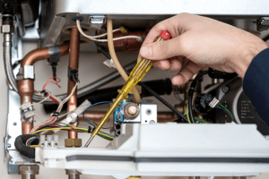man adjusting a furnace with a screwdriver.