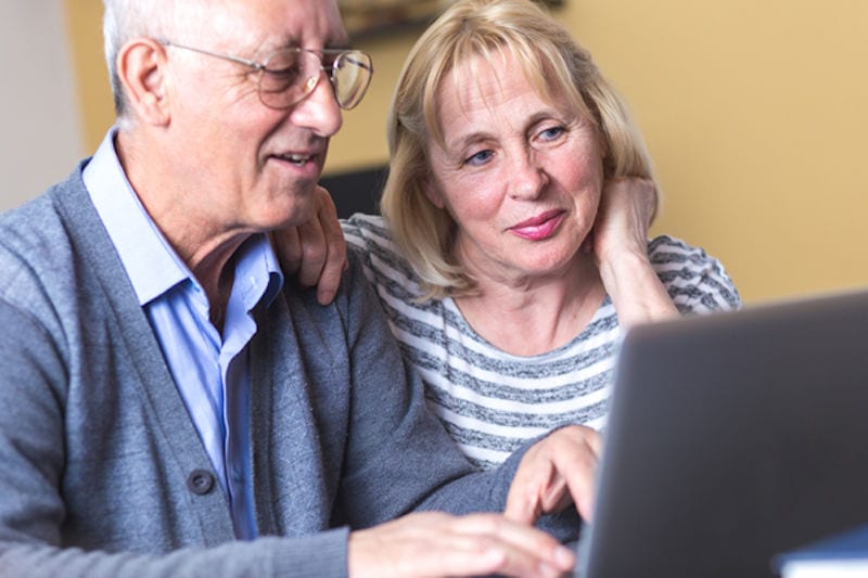 Happy senior couple using laptop at home.