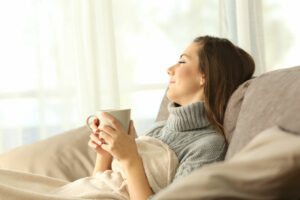 Portrait of a pensive woman relaxing sitting on a sofa in the living room in a house